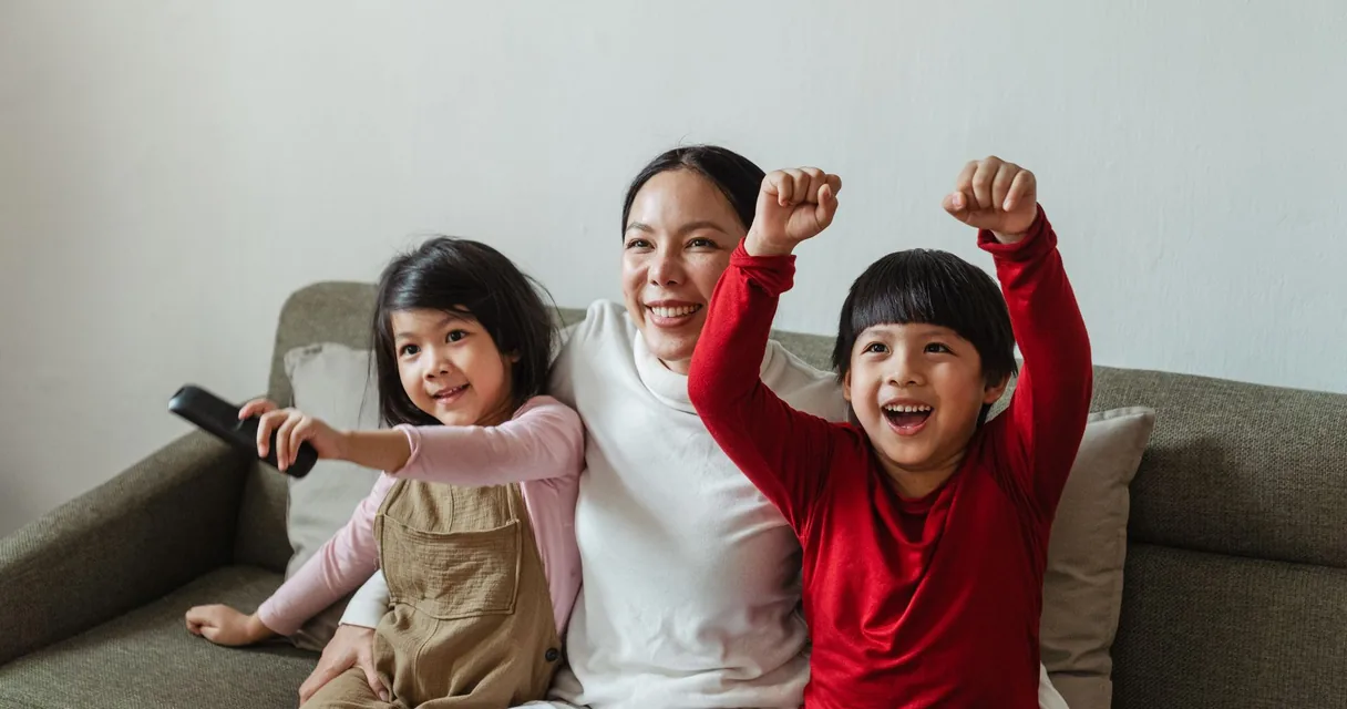 Mãe e filhos comemorando um gol no sofá durante o teste IPTV grátis